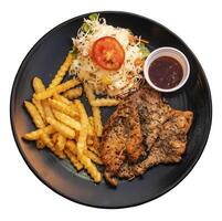 Black pepper marinated chicken fillet with potato sticks on a black plate photo