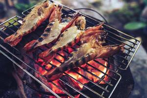 Large prawns are placed on an iron griddle and grilled over a hot coal stove. photo