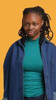 verticaal zorgeloos Afrikaanse Amerikaans jong meisje hebben positief welzijn, gevoel blij, geïsoleerd over- studio achtergrond. portret van verheugd vrouw staand trots, gevoel zelfverzekerd, camera een video