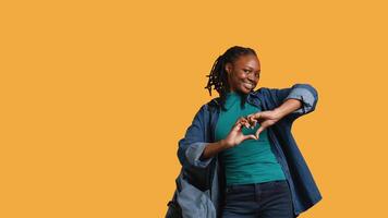 Portrait of friendly smiling african american woman doing heart symbol shape gesture with hands, being affectionate. Cheerful nurturing person showing love gesturing, studio background, camera B video