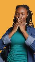 Vertical African american woman covering eyes, ears and mouth with hands, imitating the three wise monkeys. Girl doing do not see, do not hear and do not speak gesturing concept, studio background, camera A video