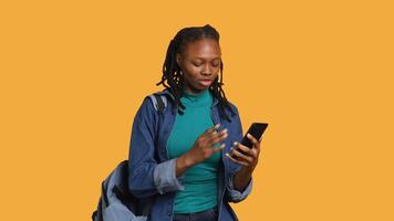 Upset african american woman arguing with friends during teleconference meeting on smartphone, studio background. Annoyed girl fighting on mobile phone call with mates, camera A video