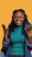 Vertical Upbeat african american teenager goofing around, feeling joyous, isolated over studio background. Portrait of happy young girl acting silly, showing positive demeanor, camera A video