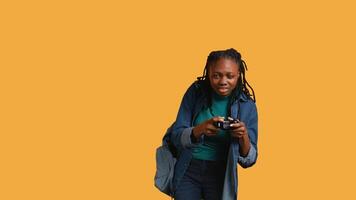 African american gamer holding controller, focused on finishing difficult game level. Woman gaming with gamepad, solving quests, isolated over studio backdrop, camera B video