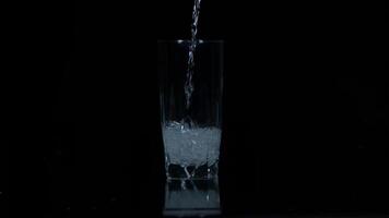 Pouring water into a glass beaker in slow motion video