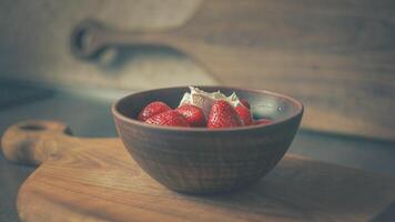 Juicy strawberries with cream in a clay plate on a wooden board. POSTER 16-9 photo