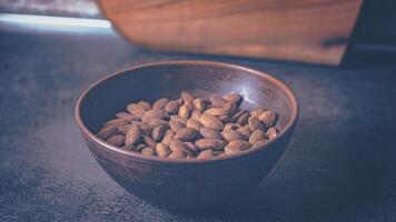 Almonds in a clay plate on the table. Brown shade.16-9 photo