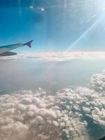 Cloudscape against blue sky through air plane window. Airplane in air with blue clouds. Airplane window photo