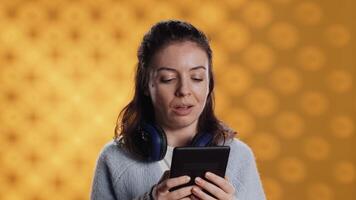 Voice actor reading ebook in entertaining manner in front of audience, portraying character, studio background. Woman reenacting digital novel for spectators, reading from tablet screen, camera A video