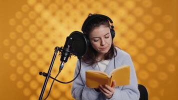 dama hojeada páginas, haciendo narración leyendo de libro a Produce audio libro. voz actor preparando a utilizar cuentacuentos habilidades a entretener audiencia mientras grabación novedoso, estudio fondo, cámara si video