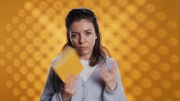 Disappointed woman bashing book, showing thumbs down hand sign, isolated over studio background. Upset bookworm dissatisfied with new novel, giving negative review, camera B video