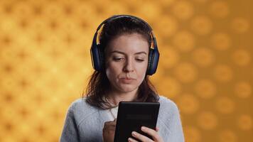 mulher vestindo fones de ouvido, praticando Novo língua vocabulário usando conectados aplicativo em tábua, isolado sobre estúdio fundo. senhora Falando estrangeiro frases, lendo eles em dispositivo tela video