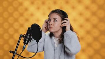 mujer con auriculares en comenzando trabajo, narrando libro palabra para palabra a Produce audio libro. narrador poniendo auriculares en, utilizando mic a Produce digital grabación de novedoso, estudio fondo, cámara un video