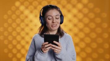 Voice actor smiling while reading ebook, portraying proud and sassy character, studio background. Woman reenacting digital novel, interpreting cheerful protagonist, reading text from tablet, camera B video