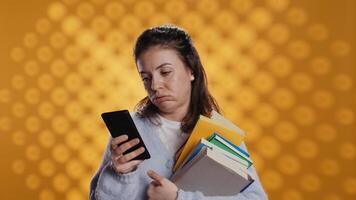 trastornado mujer participación apilar de libro, preparando para colegio examen utilizando teléfono, estudio antecedentes. estudiante con pila de libros de texto haciendo pucheros mientras investigando para Universidad deberes utilizando teléfono inteligente, cámara si video