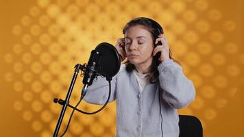 mujer con auriculares en comenzando trabajo, narrando libro palabra para palabra a Produce audio libro. narrador poniendo auriculares en, utilizando mic a Produce digital grabación de novedoso, estudio fondo, cámara un video