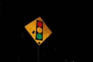 Photo of iron triangular traffic light signs at night