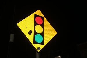 Photo of iron triangular traffic light signs at night