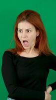 A red-haired girl in black clothes is very surprised with her mouth open, Different emotions on a green background video