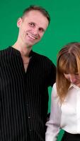 A guy and a girl in black and white clothes, Yin-Yang, talking and smiling on a green background. Vertical , We look at the camera and at each other video