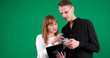 Young couple two friends family man woman in pink clothes together hold in hand use mobile cell phone point on it say wow search isolated on pastel plain light blue color background studio portrait video