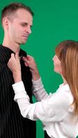 A guy and a girl in black and white clothes, Yin-Yang, talking and smiling on a green background. Vertical We look at each other video