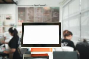 Blank white screen on modern computer monitor in coffee shop, stock photo