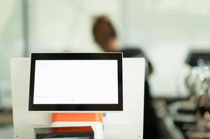 Blank white screen on modern computer monitor in coffee shop, stock photo