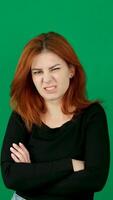 A red-haired girl in black clothes, crossing her arms over her chest, hugging herself around the waist, looks displeasedly to the side. Negative emotions video