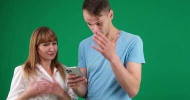 Picture of a young couple watching a funny on mobile phone, posing on isolated background video