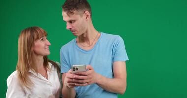 Picture of a young couple watching a funny on mobile phone, posing on isolated background video