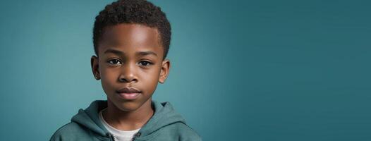 An African American Juvenile Boy Isolated On A Teal Background With Copy Space. photo