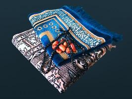 Folded Muslim prayer mat used to pay with tasbih and khajoor on black background photo