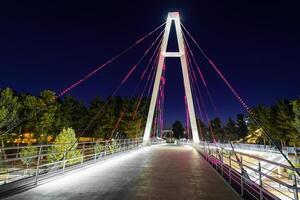 Modern footbridge with steel cables across the Anhor canal in Navruz park with illumination lights at night, Uzbekistan, Tashkent. photo