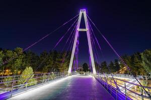 Modern footbridge with steel cables across the Anhor canal in Navruz park with illumination lights at night, Uzbekistan, Tashkent. photo