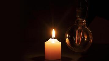 Blackout concept, turned off light bulb with no electricity hanging next to a burning candle photo