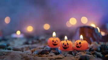 Halloween background, 3 pumpkin shaped candles in the foreground against an out of focus background photo