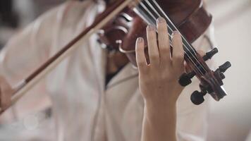 beautiful girl playing the violin while sitting on the bed at home, hand-held shooting, close-up video