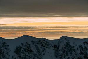 ver de el invierno puesta de sol y cubierto de nieve montañas foto