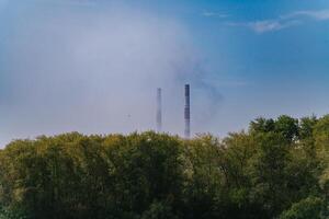 Green Village Near Factory with Tall Emitting Chimneys on a Summer Day photo