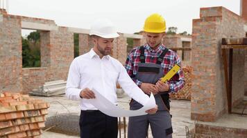 Two specialists inspect commercial, industrial building construction site. Real estate project with civil engineer video