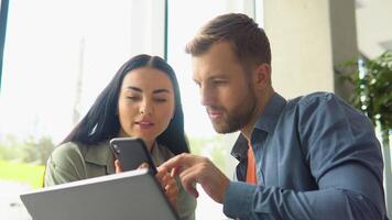 concentrado masculino empresario mirando a computadora monitor, trabajando con un joven hembra trabajador en un proyecto, personas participación un reunión con un cliente o entrevistando un trabajo candidato video