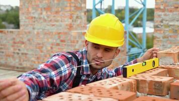 Arbeiter Steuerung Backstein Mauer mit Niveau Werkzeug. echt Nachlass Projekt mit bürgerlich Ingenieur video