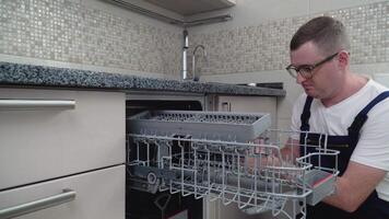 Repairman repairing dishwasher in kitchen. Repair of dishwashers video