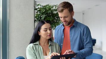 Smiling businesspeople work collaborate on computer, brainstorm over company startup at office meeting. Motivated diverse colleagues look at laptop screen discuss business project ideas together video