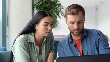 Smiling businesspeople work collaborate on computer, brainstorm over company startup at office meeting. Motivated diverse colleagues look at laptop screen discuss business project ideas together video