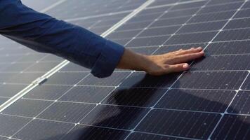 Close up of an young engineer hand is checking an operation of sun and cleanliness of photovoltaic solar panels on a sunset video