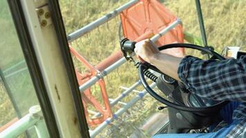 Male hands farmer driver on steering wheel combine harvest on agricultural field. View from inside tractor driver turns steering wheel agricultural machine video