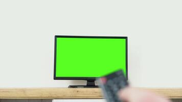 Watching chroma key TV and changing channel by remote control. Channel surfing internet TV green screen video