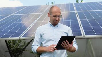 Close up portrait of male worker in protective helmet standing near solar panel video